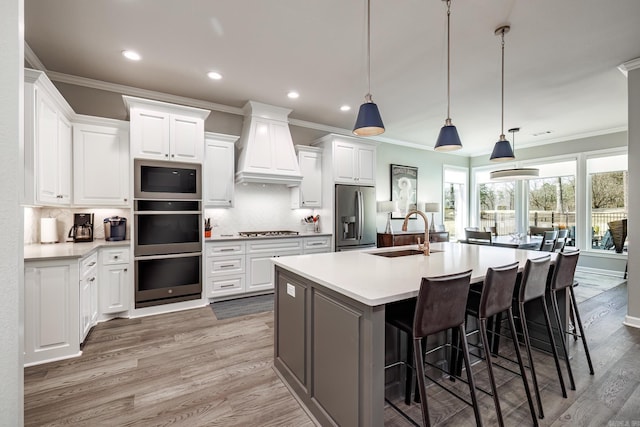 kitchen with a sink, custom exhaust hood, appliances with stainless steel finishes, and ornamental molding