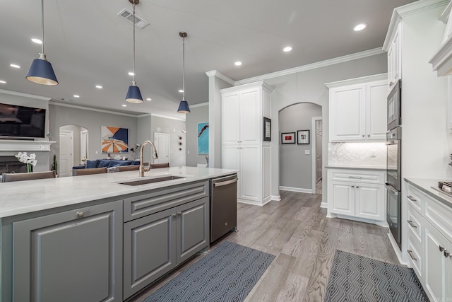 kitchen featuring a sink, visible vents, arched walkways, and gray cabinetry