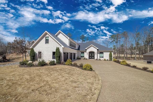 french country inspired facade featuring a garage, brick siding, and concrete driveway