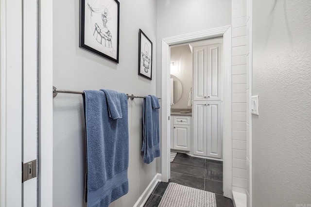 bathroom with a textured wall and baseboards