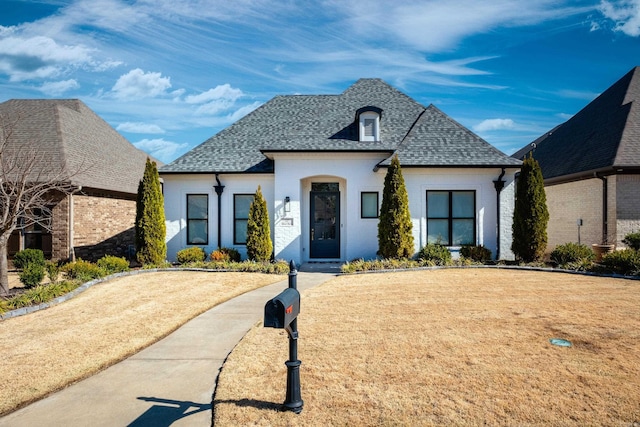 french country style house featuring a shingled roof