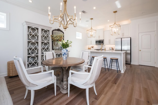 dining room featuring wood finished floors, visible vents, baseboards, recessed lighting, and crown molding