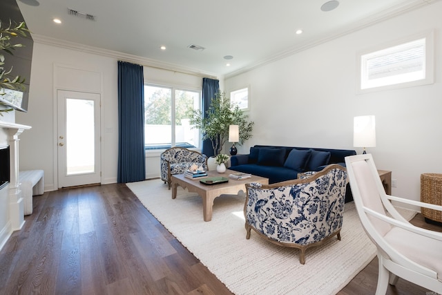 living room with visible vents, a fireplace, wood finished floors, and crown molding