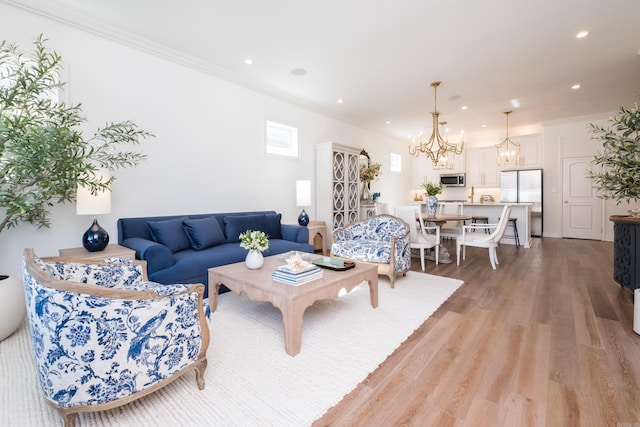 living room featuring light wood finished floors, recessed lighting, an inviting chandelier, and ornamental molding