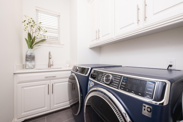 clothes washing area with cabinet space, washing machine and dryer, dark tile patterned floors, and a sink