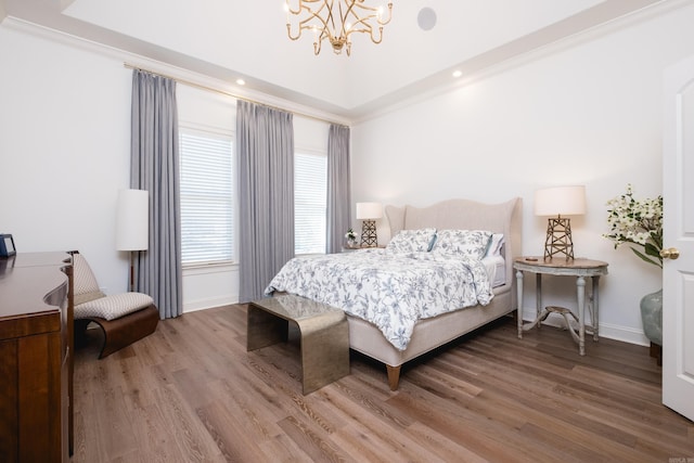 bedroom with a notable chandelier, crown molding, baseboards, and wood finished floors