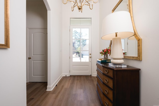 entryway with arched walkways, baseboards, and wood finished floors