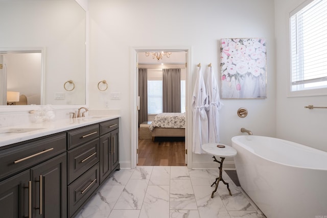 ensuite bathroom with a freestanding tub, marble finish floor, ensuite bathroom, a sink, and double vanity