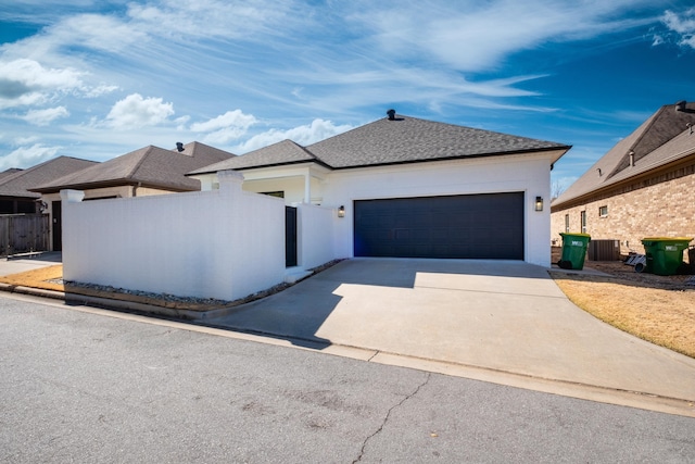 view of front of home featuring driveway, central AC unit, an attached garage, and fence