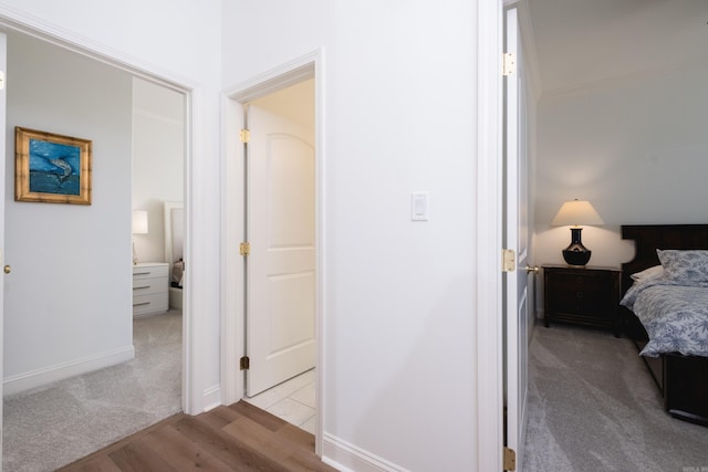 carpeted bedroom featuring baseboards and wood finished floors