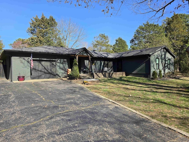 view of front of home with a garage, a front yard, brick siding, and driveway