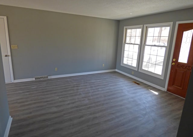 foyer entrance with visible vents, dark wood-type flooring, and baseboards