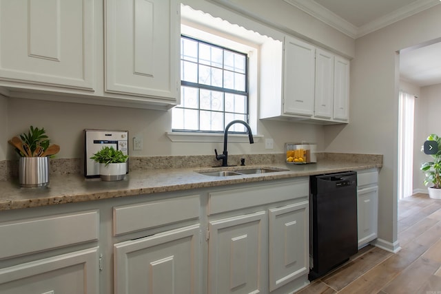 kitchen featuring light wood finished floors, ornamental molding, a sink, black dishwasher, and white cabinetry