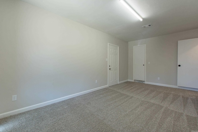 empty room with visible vents, light colored carpet, and baseboards