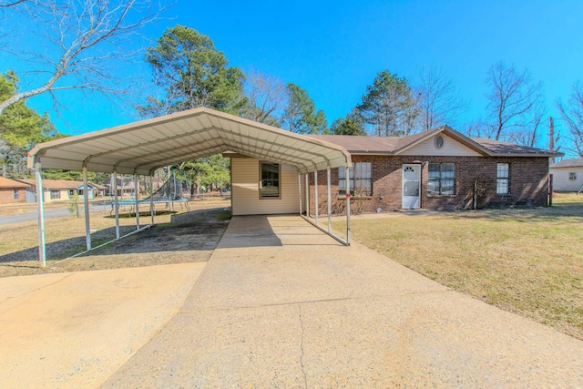 view of front of property with driveway, brick siding, a detached carport, and a front yard