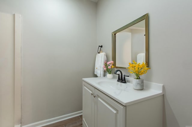 bathroom with baseboards, wood finished floors, and vanity