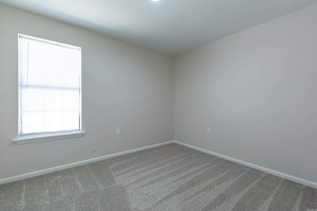 carpeted spare room featuring baseboards