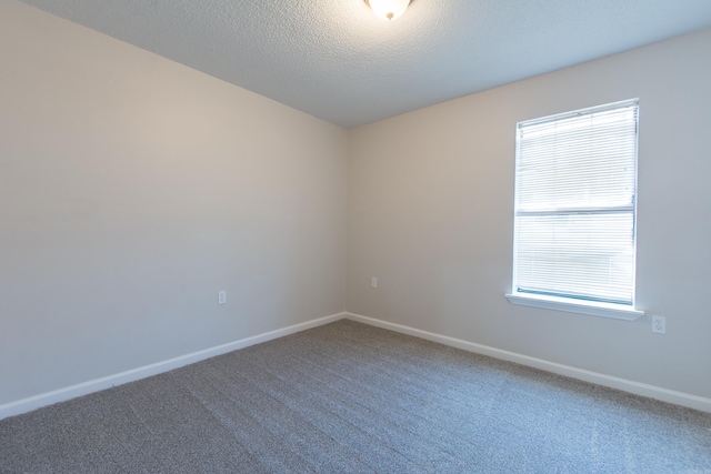 carpeted spare room featuring a textured ceiling and baseboards