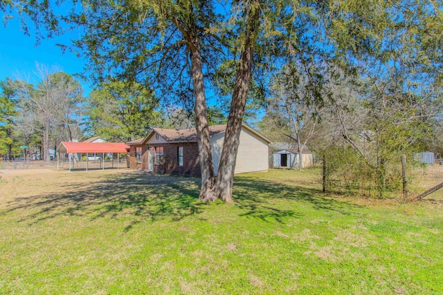 view of yard with fence, an outbuilding, a carport, and a shed