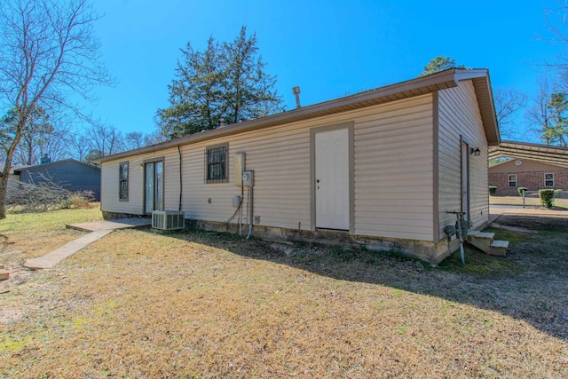 rear view of property featuring central air condition unit and a lawn