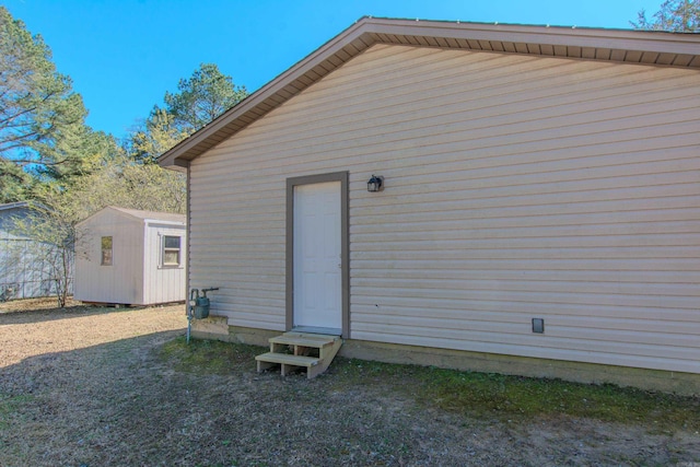 back of property featuring a storage unit, an outdoor structure, and entry steps