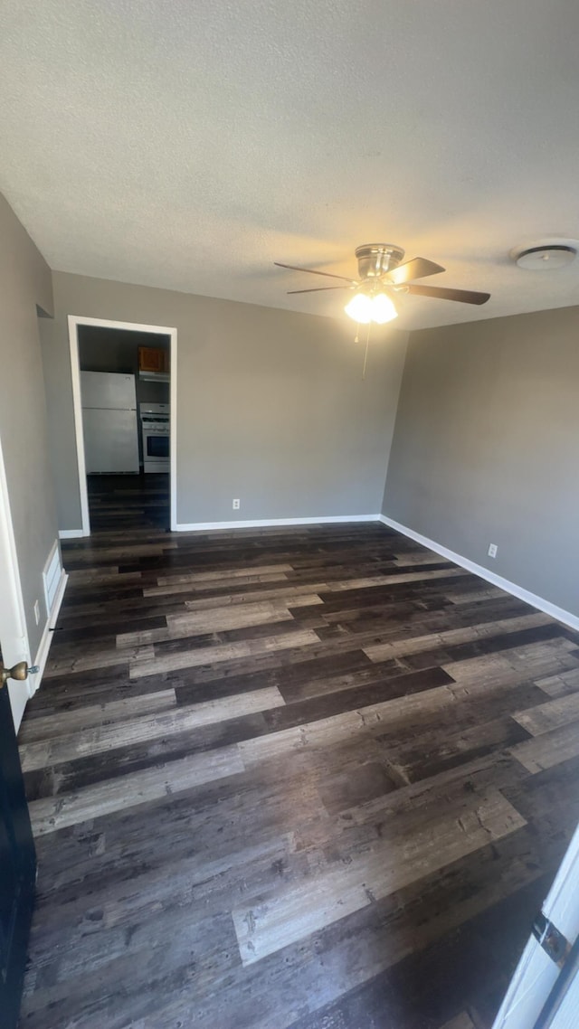 spare room featuring dark wood finished floors, a textured ceiling, and baseboards