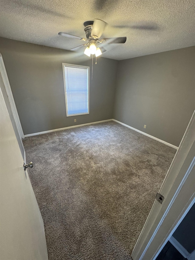 carpeted spare room featuring a textured ceiling, baseboards, and ceiling fan