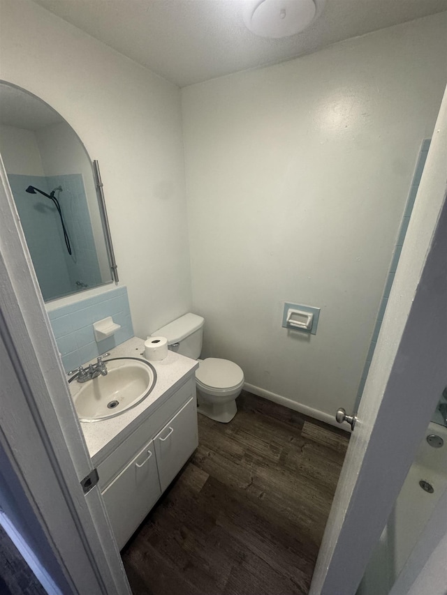 bathroom featuring vanity, wood finished floors, baseboards, a shower, and toilet