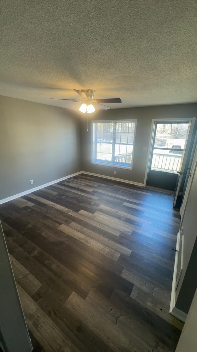 spare room featuring ceiling fan, baseboards, a textured ceiling, and dark wood finished floors