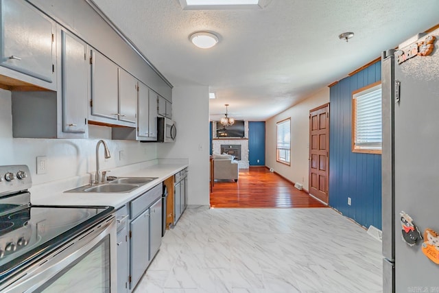 kitchen with marble finish floor, appliances with stainless steel finishes, gray cabinets, and a sink