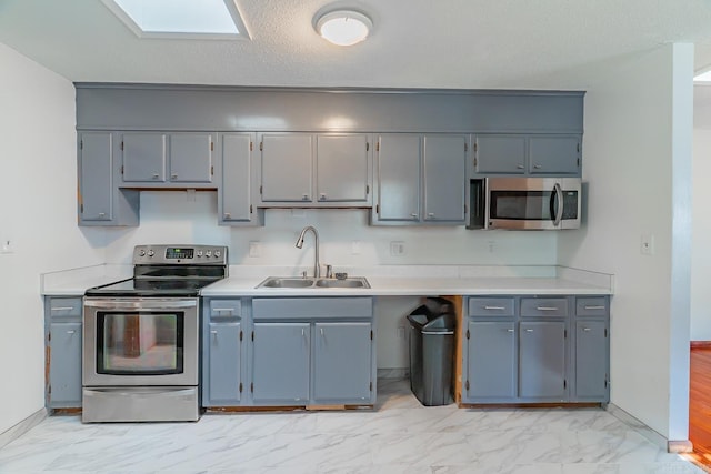 kitchen with a sink, light countertops, marble finish floor, and stainless steel appliances