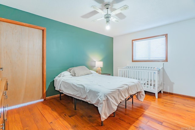 bedroom with a closet, ceiling fan, baseboards, and wood-type flooring