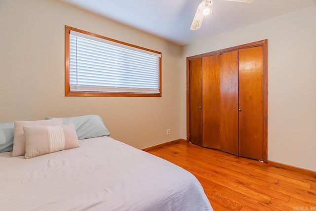 bedroom featuring light wood-type flooring, baseboards, and a closet