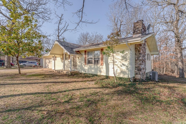 view of front of property featuring central AC unit, an attached garage, a chimney, and a front yard