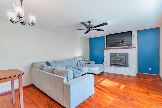 living area featuring ceiling fan with notable chandelier, baseboards, and wood-type flooring