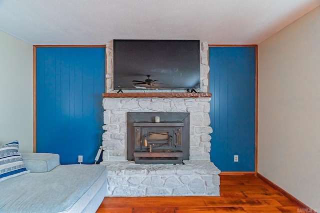 living area with a ceiling fan, wood finished floors, baseboards, and a textured ceiling