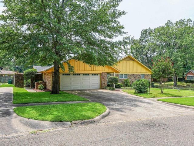 ranch-style home featuring aphalt driveway, an attached garage, and a front yard