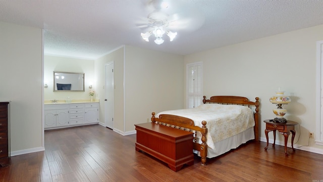 bedroom with baseboards, a textured ceiling, ensuite bath, and dark wood-style flooring