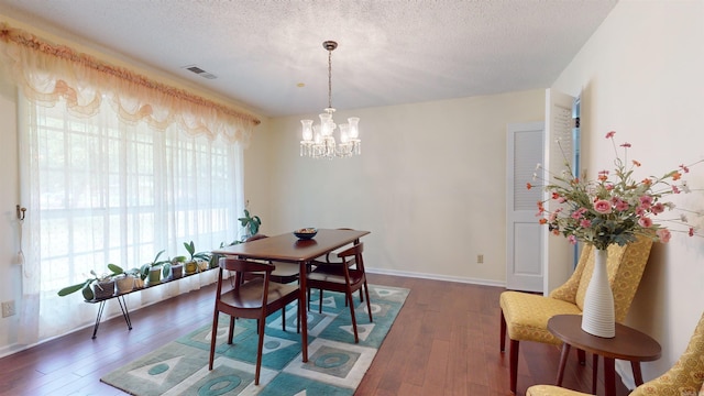 dining room featuring visible vents, wood-type flooring, a textured ceiling, and a chandelier