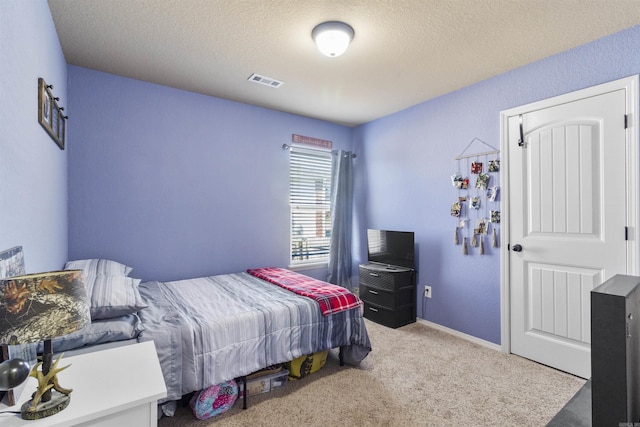 carpeted bedroom with visible vents, a textured ceiling, and baseboards