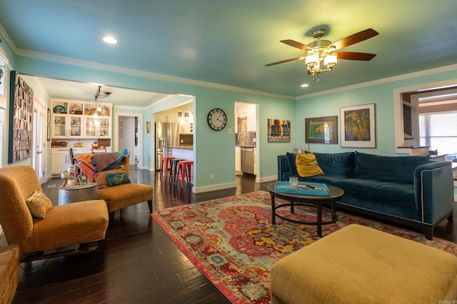 living area featuring dark wood-style floors, baseboards, recessed lighting, ornamental molding, and ceiling fan with notable chandelier