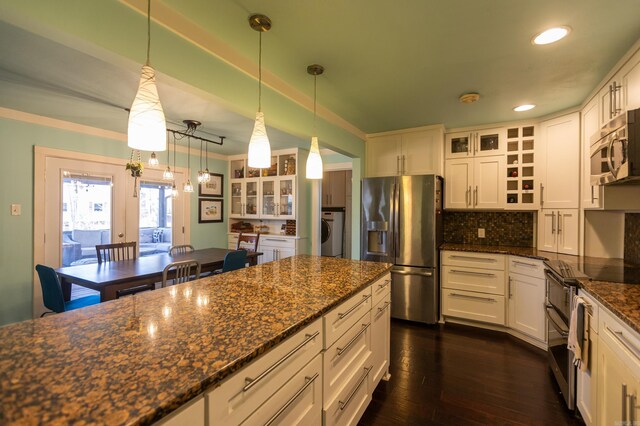 kitchen with dark wood-style floors, washer / clothes dryer, decorative backsplash, glass insert cabinets, and appliances with stainless steel finishes