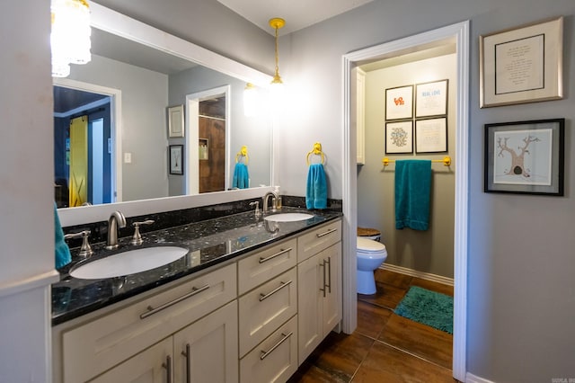 full bathroom with a sink, baseboards, toilet, and double vanity