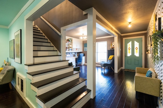 entrance foyer featuring baseboards, dark wood finished floors, stairway, ornamental molding, and a textured ceiling