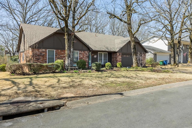 view of front facade featuring brick siding, an attached garage, a front lawn, and roof with shingles