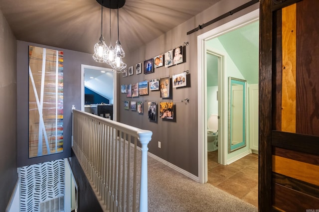 hall featuring an upstairs landing, an inviting chandelier, carpet flooring, tile patterned flooring, and baseboards