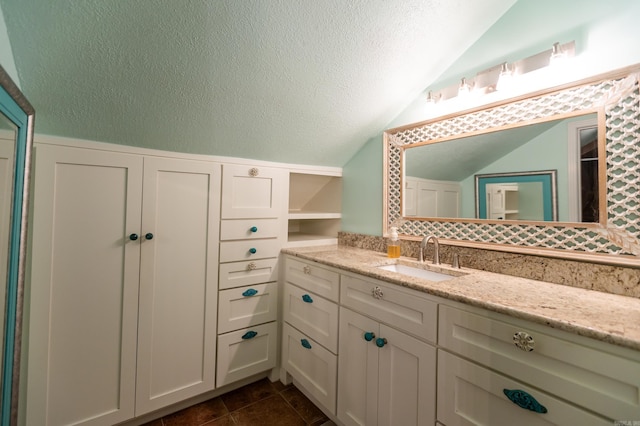 bathroom featuring tile patterned floors, a textured ceiling, vanity, and lofted ceiling