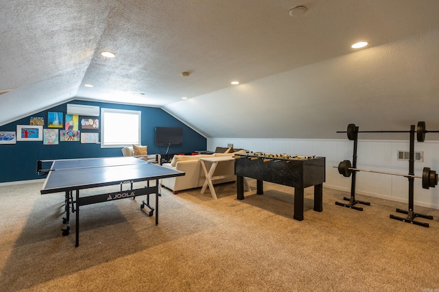 game room featuring visible vents, carpet, a wall unit AC, vaulted ceiling, and a textured ceiling