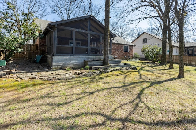 rear view of house with a yard, fence, and a sunroom