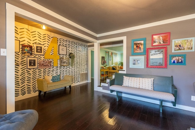 living area featuring visible vents, an accent wall, baseboards, and wood finished floors